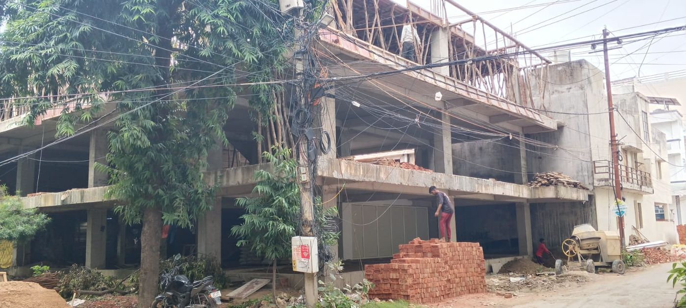 Nivaa Maple Court from the street on 24 September 2026: the stilt level, two cast slabs, and shuttering for the second floor